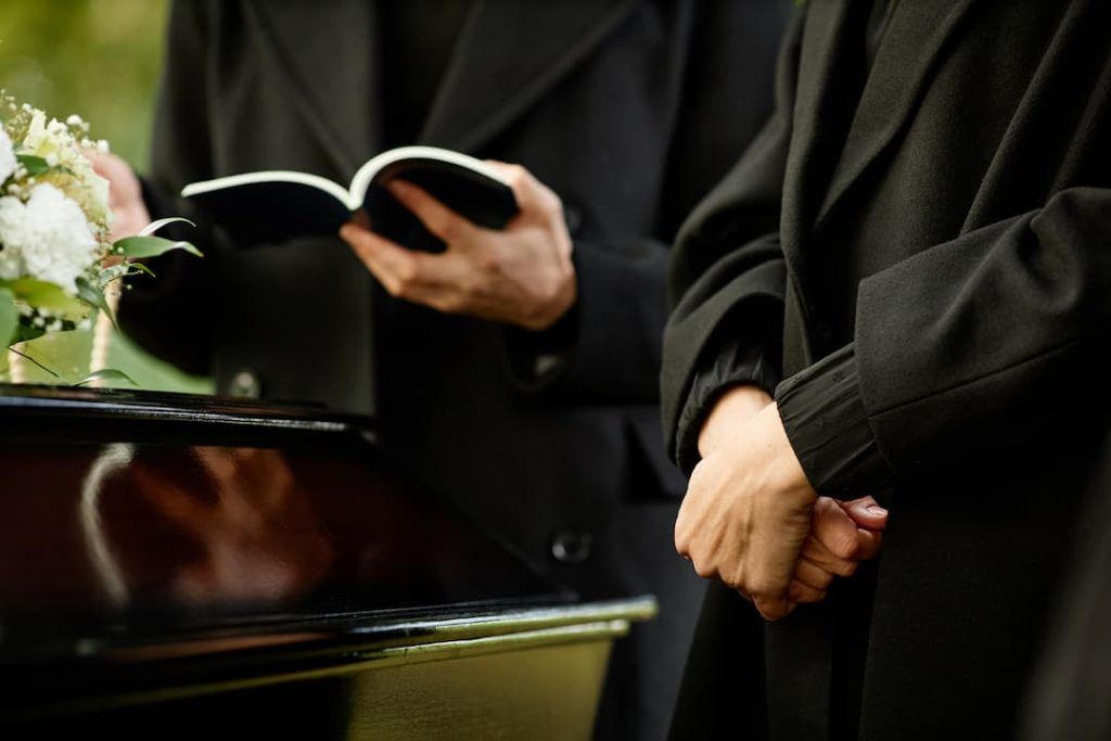 Priest reading prayer from order of service during funeal